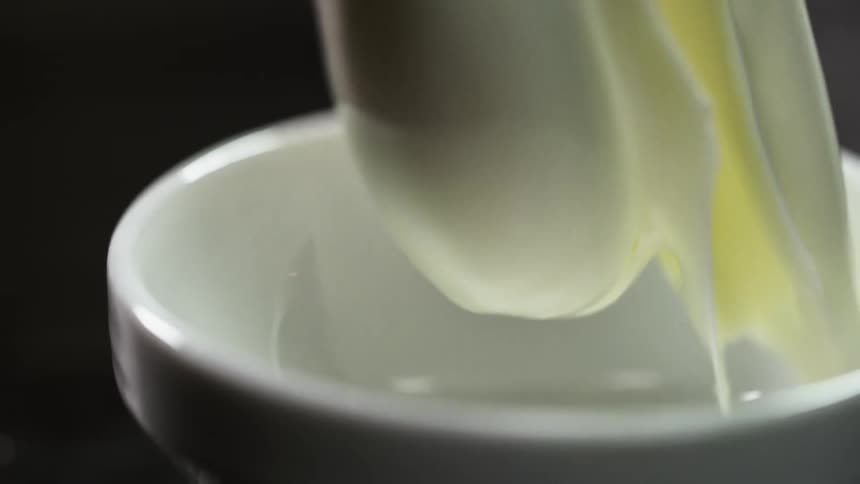 A large dollop of cream falls into a small bowl