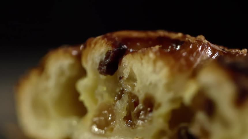 A bread pastry covered in raisins and topping