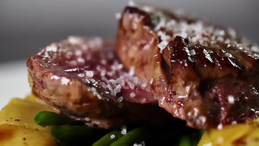 Salt falling on a plate with meat and vegetables