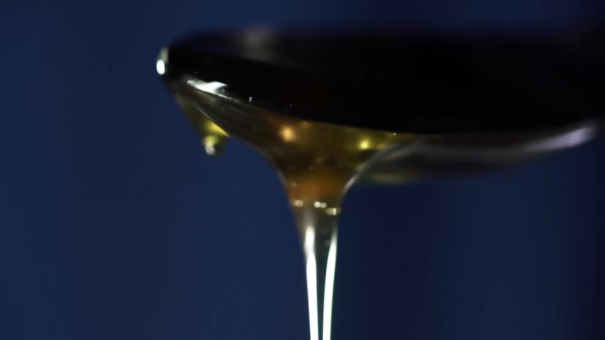 Honey in a jar being scooped up by a spoon