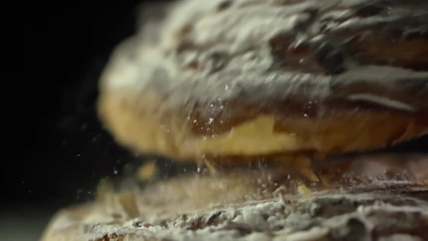 A pastry is dropped and bounces of another pastry while releasing flakes and sugar