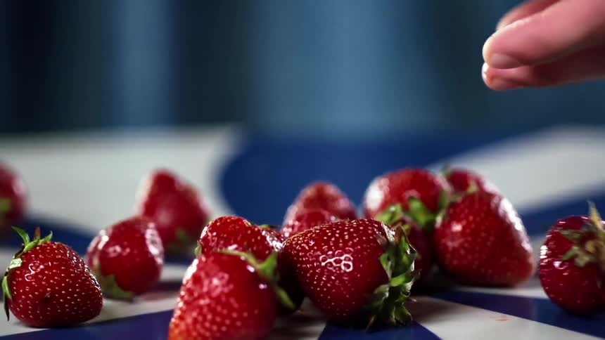 Gently dropping strawberries on a blue and white spiral table
