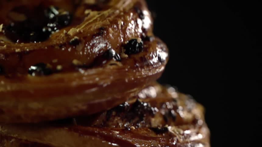 Close up of a cinnamon bun falling on another bun