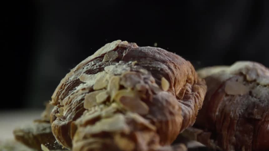 A piece of bread covered in shaved nuts drops onto a pile of food