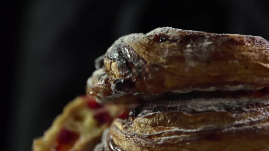 Sweet croissant rolls covered in confectioners sugar and filled with jam fall onto each other