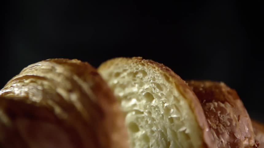 Close up of a croissant cut in half on the dark background