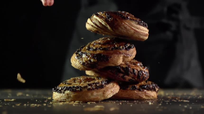Sweet rolled buns pile up onto each other over a table filled with crumbs