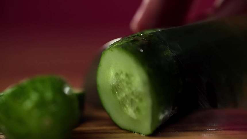 A person slicing a cucumber