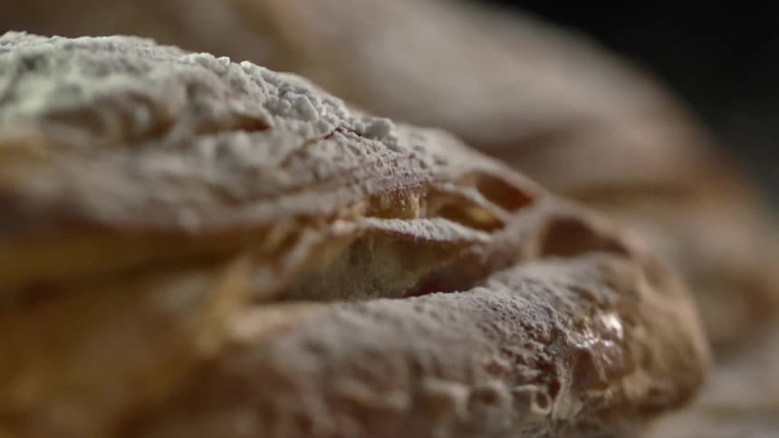 Powdered sugar goes flying as a pastry is dropped on a wood counter
