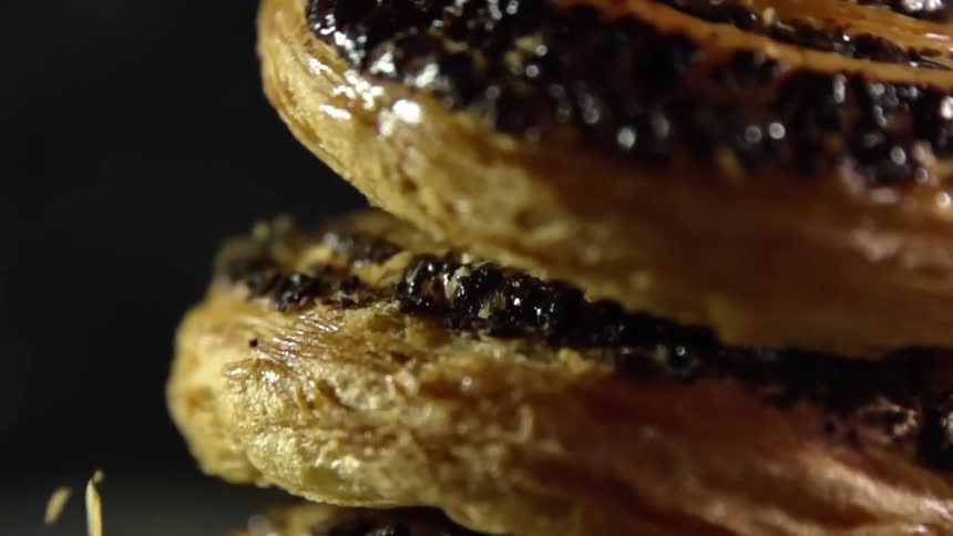 Pastry falls onto another pastry as crumbs fall off