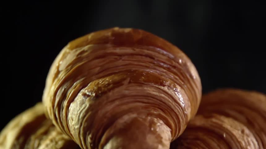 A croissants is dropped on top of two others and bounces before coming to a rest