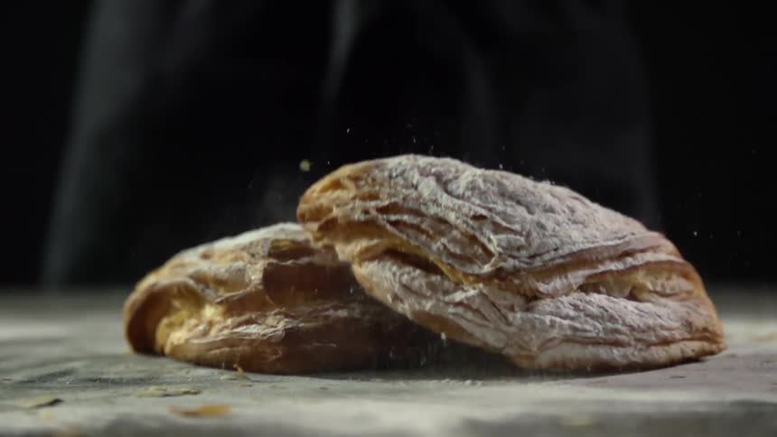 Sweet pastries covered in confectioners sugar falling in a table