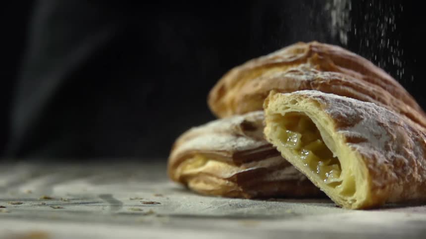 Powdered sugar is sprinkled onto a pastry