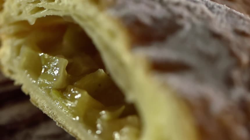 A pastry with powdered sugar on top and a fruit filling inside