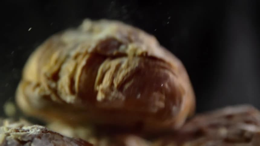 A pastry bread drops onto a pile of similar food items