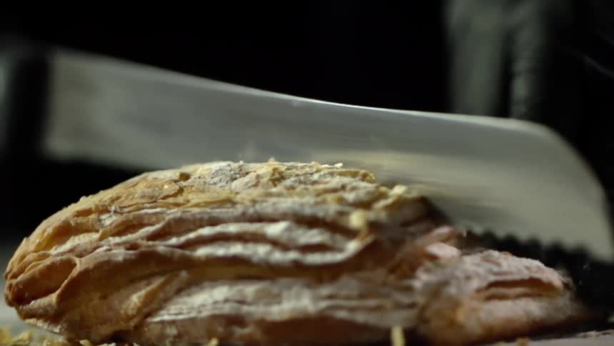 A serrated knife cuts through a bread pastry