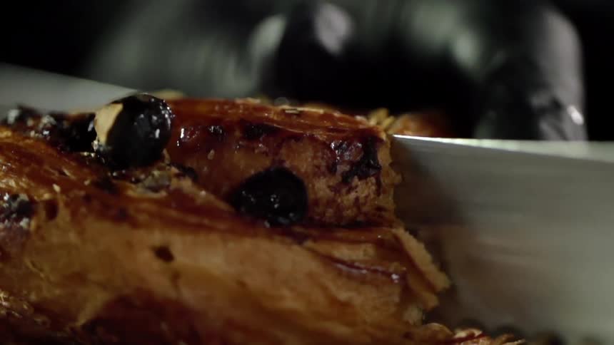 A pastry is cut in half with a knife