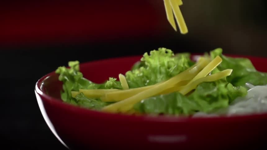 Short noodles fall atop vegetables in a red bowl
