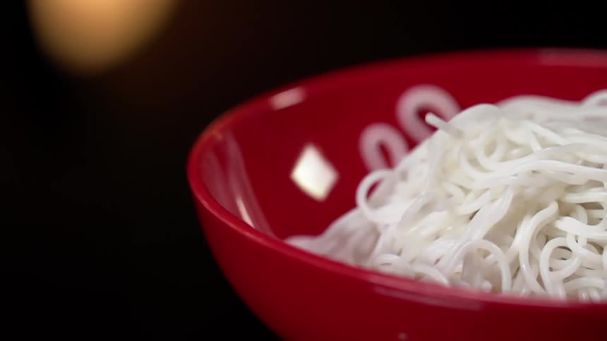 White noodles drop and fill a red bowl