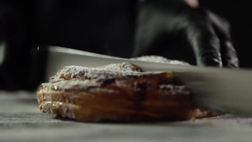 A person is cutting a pastry in half
