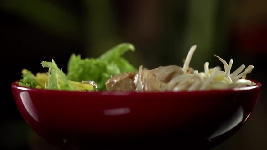 Chicken falling in to a bowl of vegetables