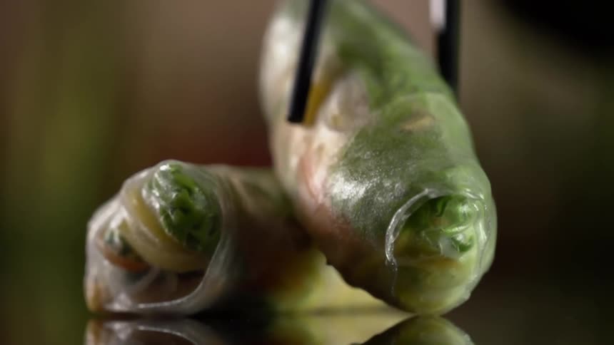 An egg roll is plated with chopsticks