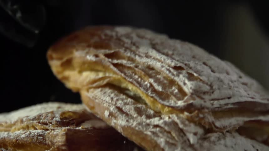 A pastry dusted with powdered sugar is placed on top of another one