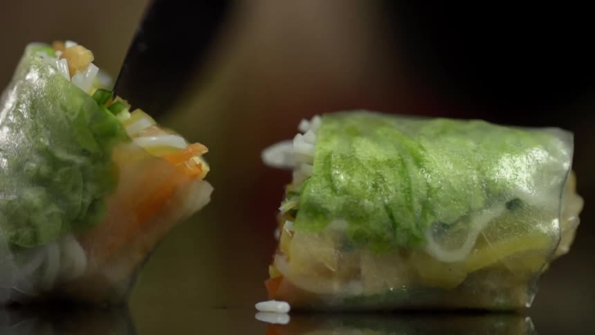 A person wearing a glove moves half of a sliced food wrap