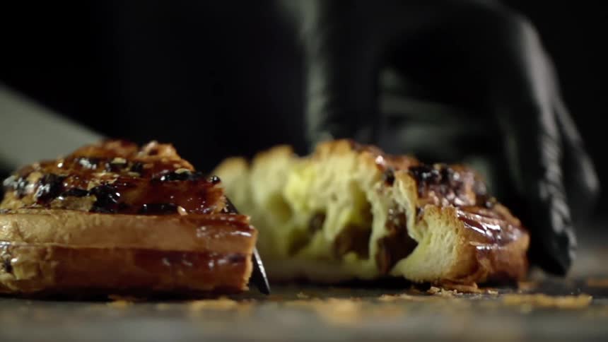 A person cutting a pastry in half