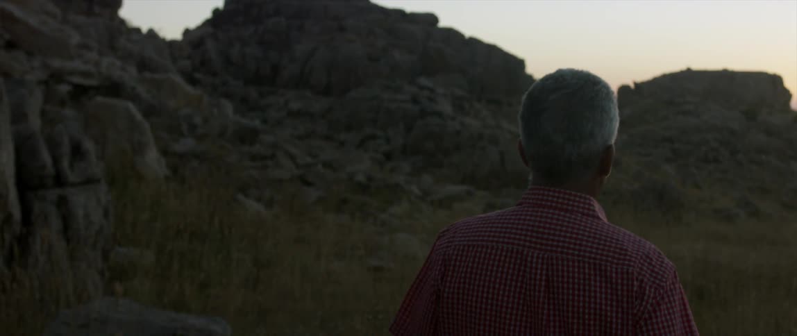 A man is walking over to a hill at sunset