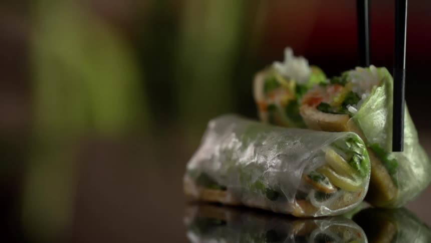 A cut half of a spring roll is placed on its wrapped end next to another spring roll resting on its side