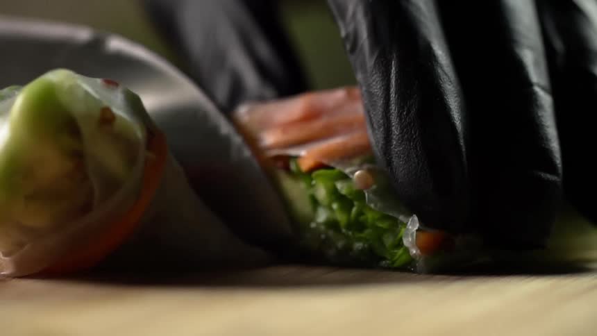 A large knife cuts a seafood wrap in half