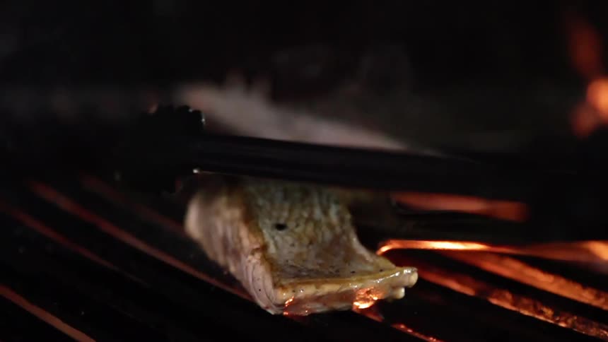Fish being set on a grill with open flames
