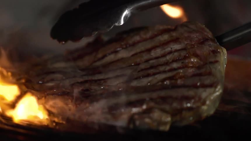 A deliciously moist piece of steak is laid atop an open flame grill