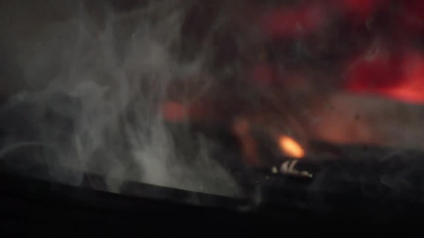 Meat is taken off of a grill with large flames