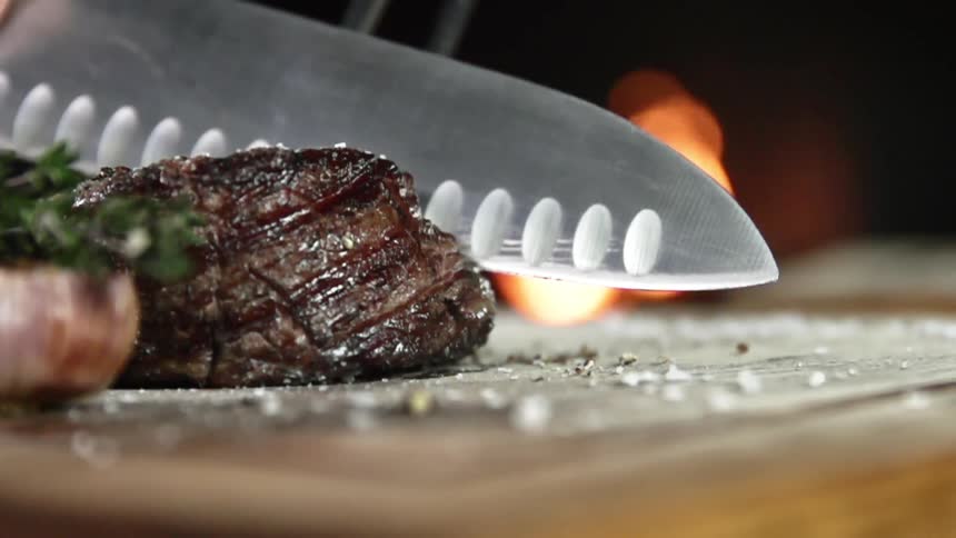 A steak filet is cut on a cutting board covered in large chunks of sea salt