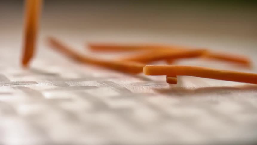 Carrot sticks fall onto a sheet of paper