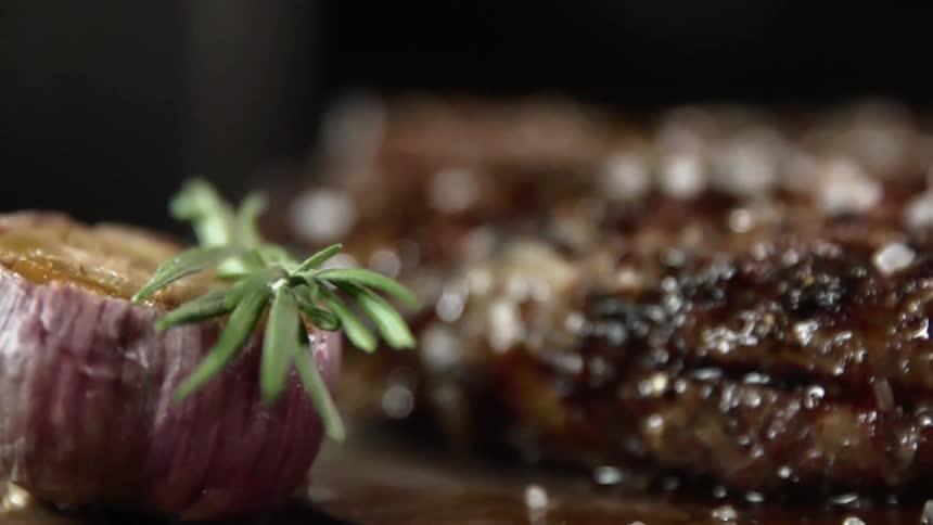 Rosemary and root vegetable garnish plate near glistening well seasoned beef