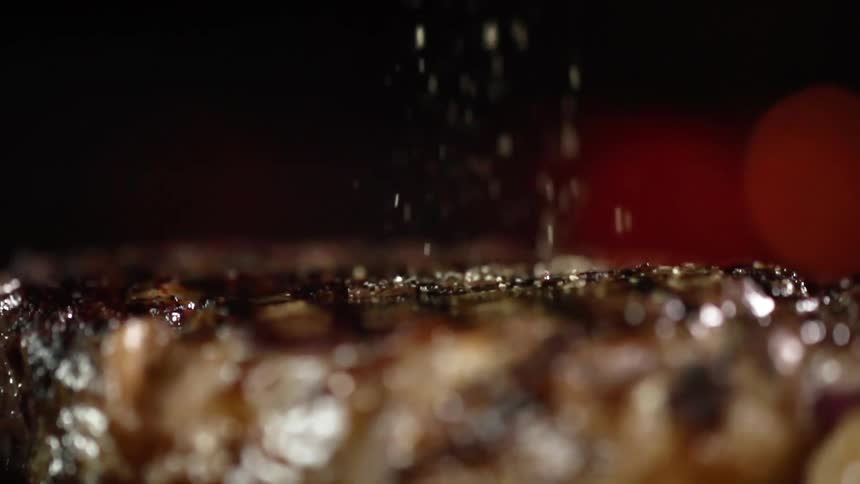 Seasoning is being sprinkled on the steak