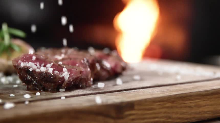 Coarse salt is sprinkled on a piece of steak