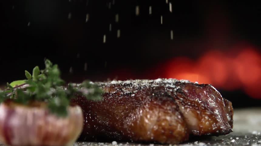 Salt is being added to grilled juicy steak