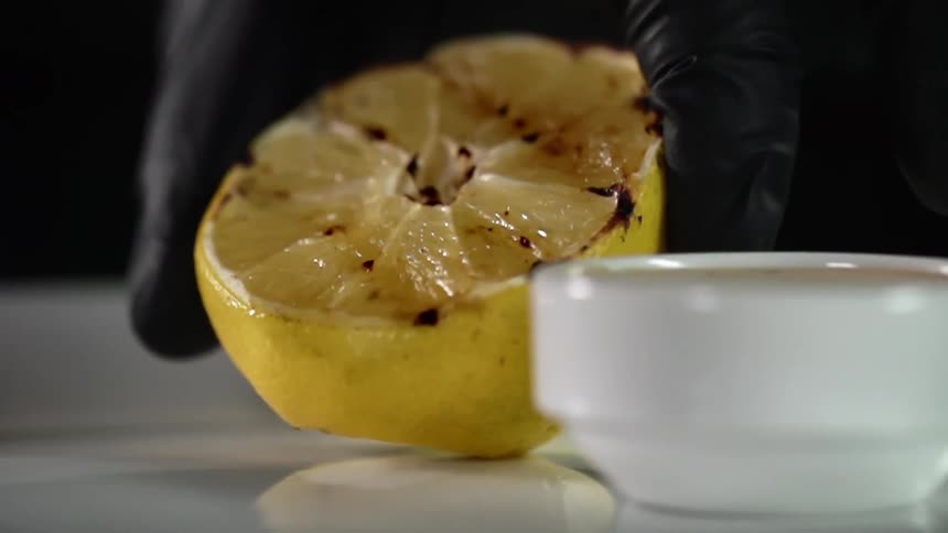 A person sets a grilled lemon on a plate