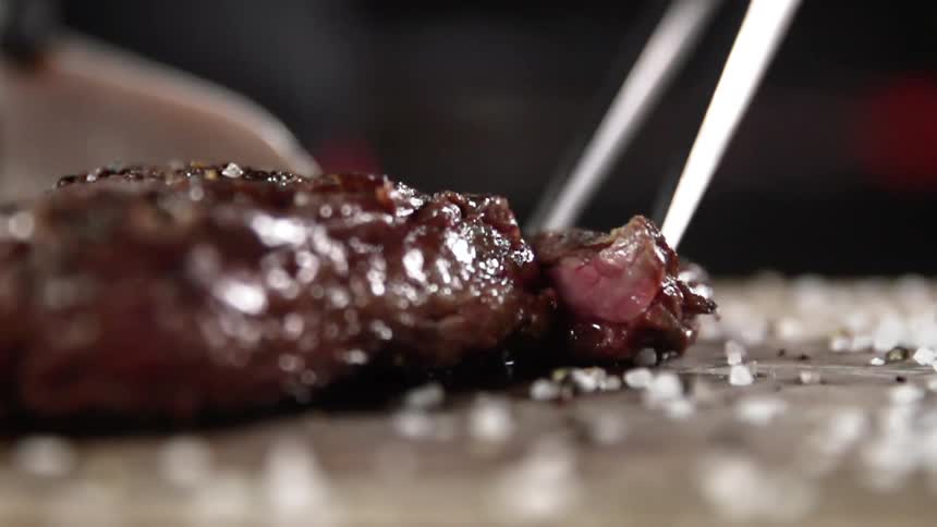 Juicy steak is being cut by a knife