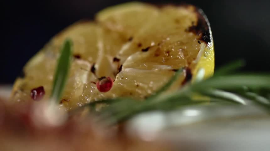 A cooked lemon and a green herb on a plate