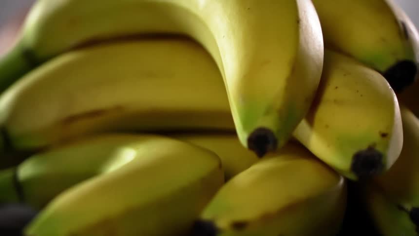 A pile of about a dozen ripe bananas are stacked on top of each other
