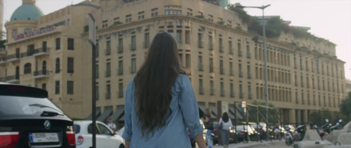 People are walking down a city block past buildings