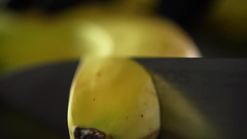 A knife is used to slice a piece of banana