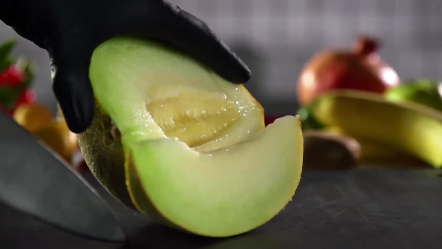 A person is cutting a cantaloupe with a knife
