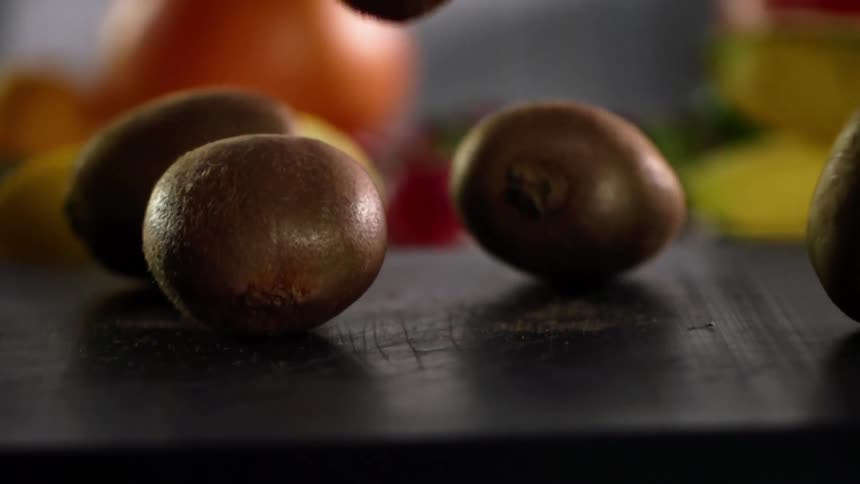 Tropical exotic fruit falls and bounces over a dark wooden board