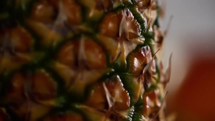 The skin of an uncut pineapple glistens with with moisture